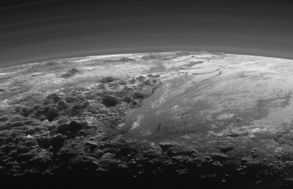 نظرة مقربة: تظهر في هذه الصورة الجبال الجليدية الكبيرة لبلوتو والسهول الجليدية المتجمدة بالإضافة إلى طبقات من الضباب. وقد تم التقاط هذه الصورة بعد 15 دقيقة فقط من وصول نيو هورايزنز إلى أقرب نقطة لها من بلوتو بتاريخ 14 يوليو/تموز 2015. وبينما كانت المركبة تنظر إلى الوراء باتجاه الشمس، تمكنت من التقاط هذه المشاهد المقربة لغروبها والتي تظهر فيها الجبال الجليدية الوعرة بالإضافة إلى السهول الجليدية المسطحة التي تمتد باتجاه أفق بلوتو.  يطلق على هذه المساحة المسطحة اسم غير رسمي هو السهل الجليدي سبوتنيك بلاينم Sputnik Planum(إلى جهة اليمين). وتحيط بهذا السهل من جهة الغرب سلسلة من الجبال الوعرة التي يصل ارتفاعها إلى 11 ألف قدم (أي 3500 كم)، بما فيها جبال نورغاي Norgay Montes (وهو اسم غير رسمي) التي توجد في المقدمة، وجبال هيلاريHillary Montes التي توجد في الأفق. ويتم قطع التضاريس الوعرة التي توجد إلى اليمين أي شرقي سبوتنيك، بواسطة الأنهار الجليدية التي تبدو واضحة للعيان. ويُسلَّط ضوء الخلفية على أكثر من اثني عشرة طبقة من الضباب الموجود في الغلاف الجوي الممتد والرقيق لبلوتو. تم التقاط هذه الصورة من نقطة تبعد عن بلوتو مسافة تقدر بـ 11 ألف ميل (أي 18 ألف كم)، ويقدر نطاق هذه الصورة بـ 230 ميلاً (أي 380 كم). المصدر: NASA/JHUAPL/SwRI