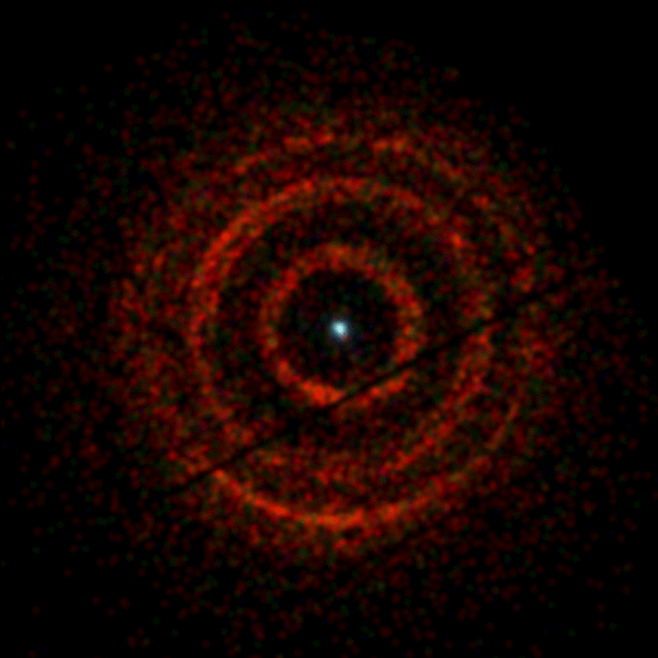 تتمحور حلقات من ضوء الأشعة السينية حول المنظومة V404 Cygni، وهي نظام ثنائي يحتوي على ثقب أسود متفجر (النقطة في وسط الصورة). تم التصوير بواسطة تلسكوب الأشعة السينية الموجود على متن القمر الصناعي سويفت التابع لناسا في الفترة من 30 حزيران/يونيو إلى 4 تموز/يوليو. هناك فجوة ضيقة تشق الحلقة الوسطية إلى اثنتين. يدل اللون على طاقة الأشعة السينية، حيث يمثل اللون الأحمر الطاقة الأدنى (800 إلى 1500 إلكترون فولت)، والأخضر الطاقة المتوسطة (1500 إلى 2500 إلكترون فولت)، وتظهر الطاقة العالية (2500 إلى 5000 فولت) باللون الأزرق، وعلى سبيل المقارنة، فإن طاقات الضوء المرئي تتراوح ما بين 2-3 فولت. تنجم الخطوط الداكنة الظاهرة قطرياً في الصورة عن نظام التصوير.  المصدر: أندرو بيردمور و NASA/سويفت (جامعة ليستر).