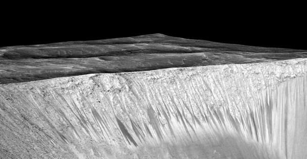 تُظهر هذه الصورة خطوطاً مُظلمة وضيقة تُسمى خطوط المنحدرات المتكررة وهي تمتد على طول جدران فوهة غارني على كوكب المريخ. يبلغ طول الخطوط الداكنة هذه بضع مئات من الأمتار، ويفترض العلماء أنها تشكّلت بسبب تدفق الماء المالح السائل على السطح. أُنتجت الصورة عبر وضع صورة مُصححة مُتعامدة (orthorectified) (RED) (إي أس بي_031059_1685) على نموذج التضاريس الرقمي (DTM) للموقع نفسه الذي أنتجته تجربة التصوير العلمي عالي الدقة (جامعة أريزونا). يبلغ مستوى التضخيم العمودي حوالي 1.5 درجة. حقوق الصورة: Credits: NASA/JPL/University of Arizona