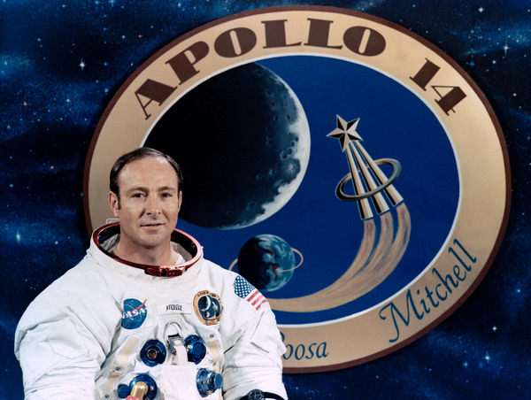 رائد الفضاء إدجار ميتشيل يقف أمام ملصق للرحلة أبوللو. حقوق الصورة: ناسا