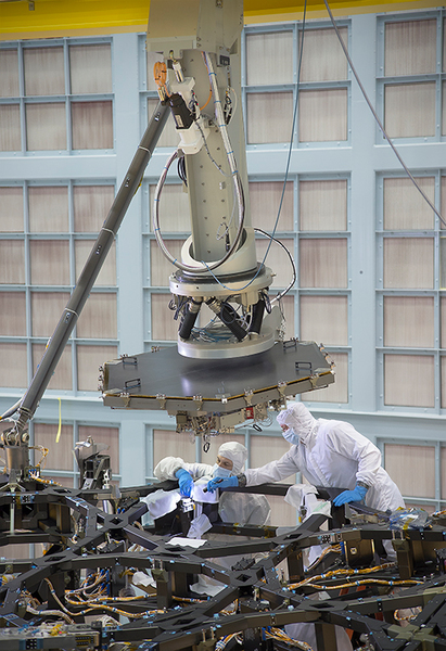 هذه الصورة ملتقطة داخل حجرة عملاقة نظيفة ومُعقّمة في مركز غودارد لرحلات الفضاء في غرينبيلت بولاية ماريلاند، حيث نرى فيها فريق عمليات تلسكوب جيمس ويب الفضائي وهو يُنهي استعداداته قُبيل البدء بعملية تركيب المرآة الأولى على هيكل التلسكوب.   المصدر: NASA/Chris Gunn